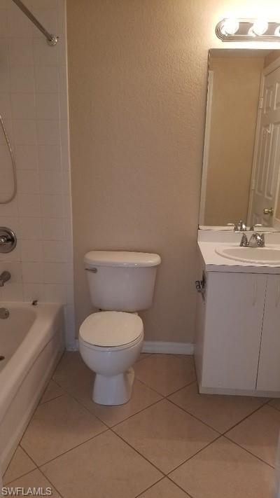 White bathtub with chrome fixtures, white square tile shower surround, and beige wall finish