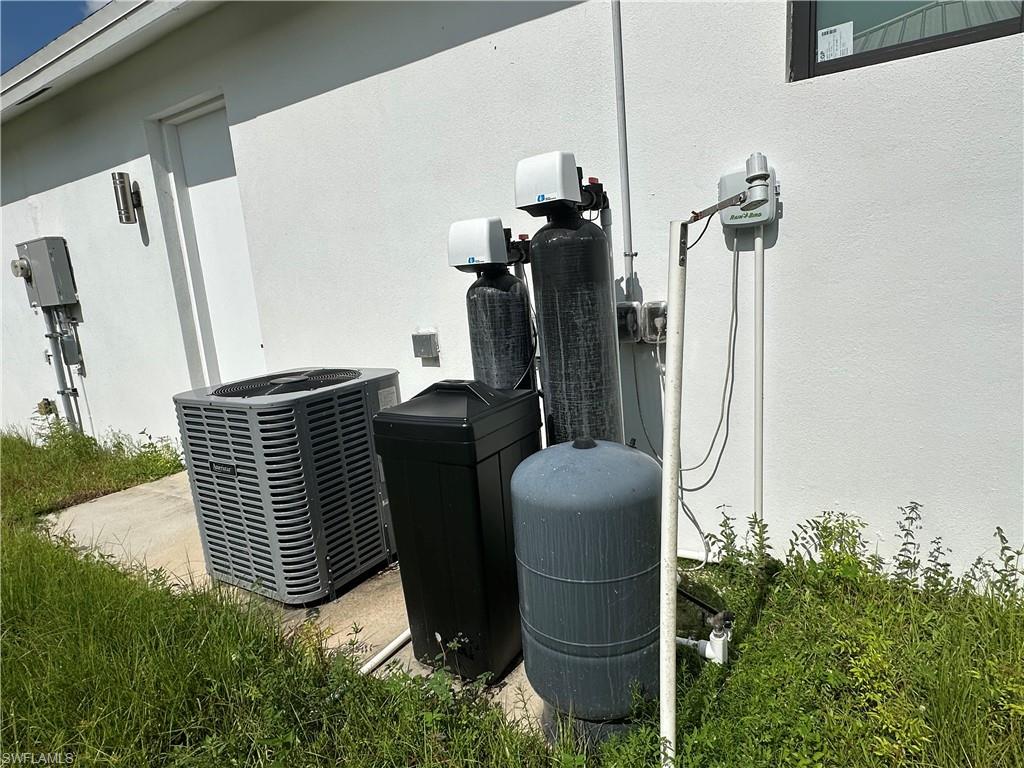 Exterior utility area featuring a central air conditioning unit, a whole-house water filtration system, and an irrigation system controller