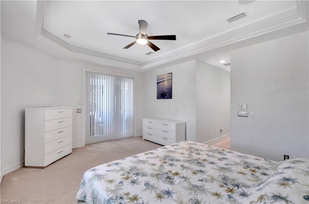 Recessed ceiling with crown molding, ceiling fan with light fixture, vertical blinds, and neutral-toned carpeting