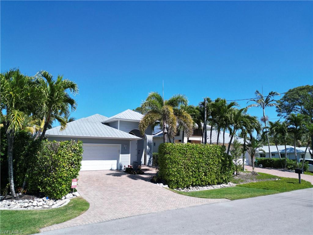 Single-story residence featuring a two-car garage, light gray exterior siding, and a metal roof