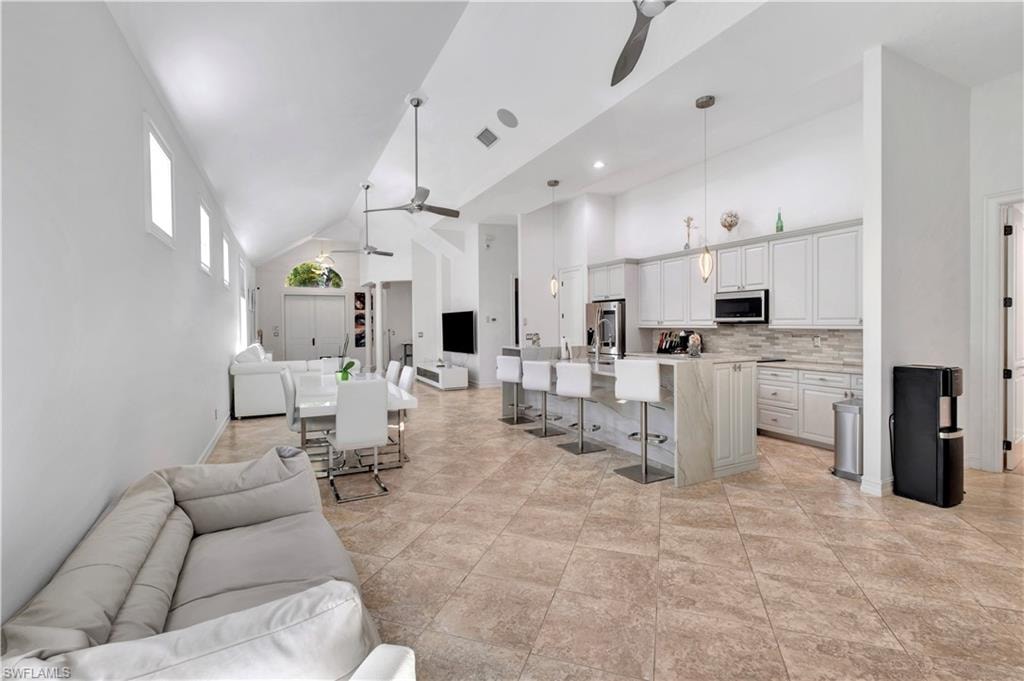 Spacious open-concept interior featuring light-toned tile flooring, vaulted ceilings, and recessed lighting