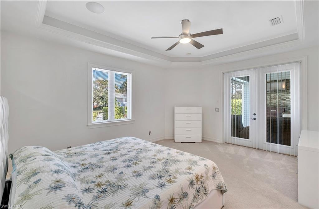 Tray ceiling with recessed lighting and a ceiling fan, plush carpet flooring, large window, and double glass doors