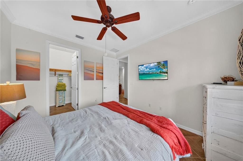 Bright interior space featuring a ceiling fan, crown molding, a built-in closet with shelving, and tile flooring