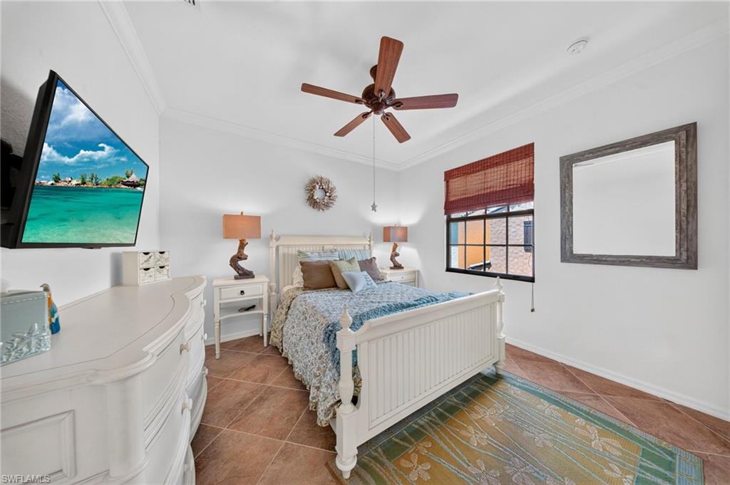 Room featuring high ceilings with crown molding, a ceiling fan with integrated lighting, and tile flooring