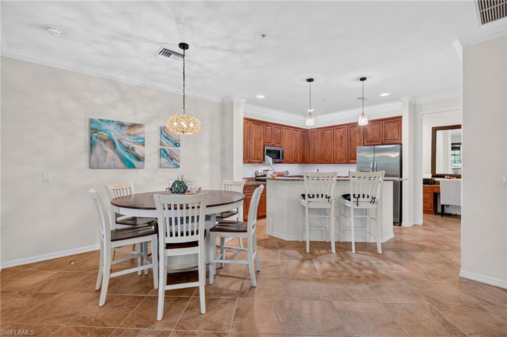 Open-concept kitchen and dining area with tile flooring, wood cabinetry, and stainless steel appliances