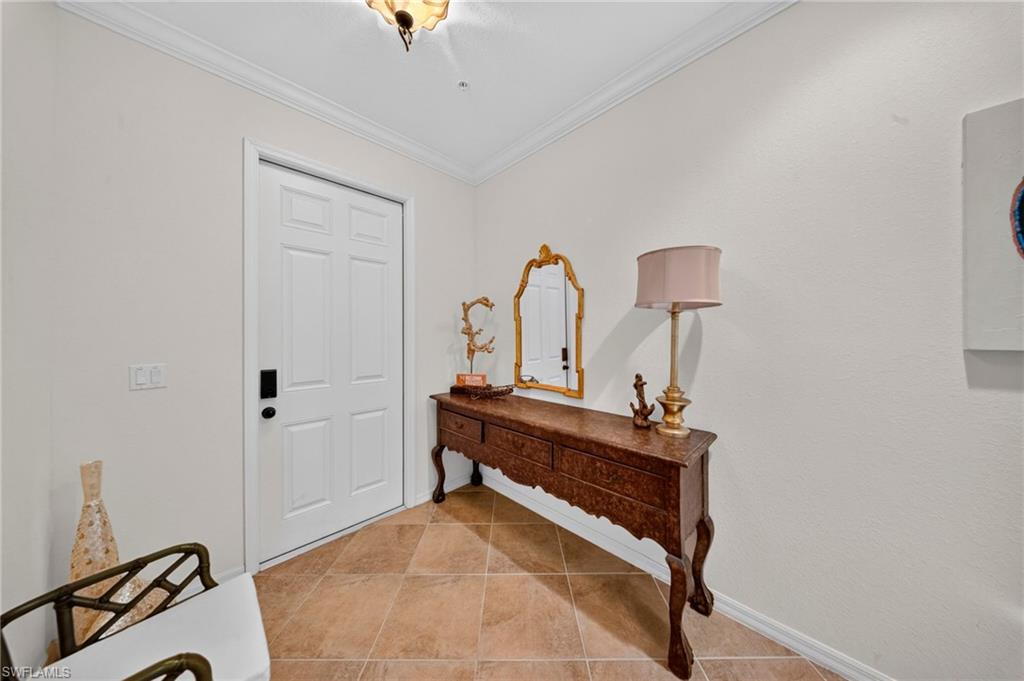 Entryway featuring a six-panel door with matte black hardware, crown molding, and tiled flooring