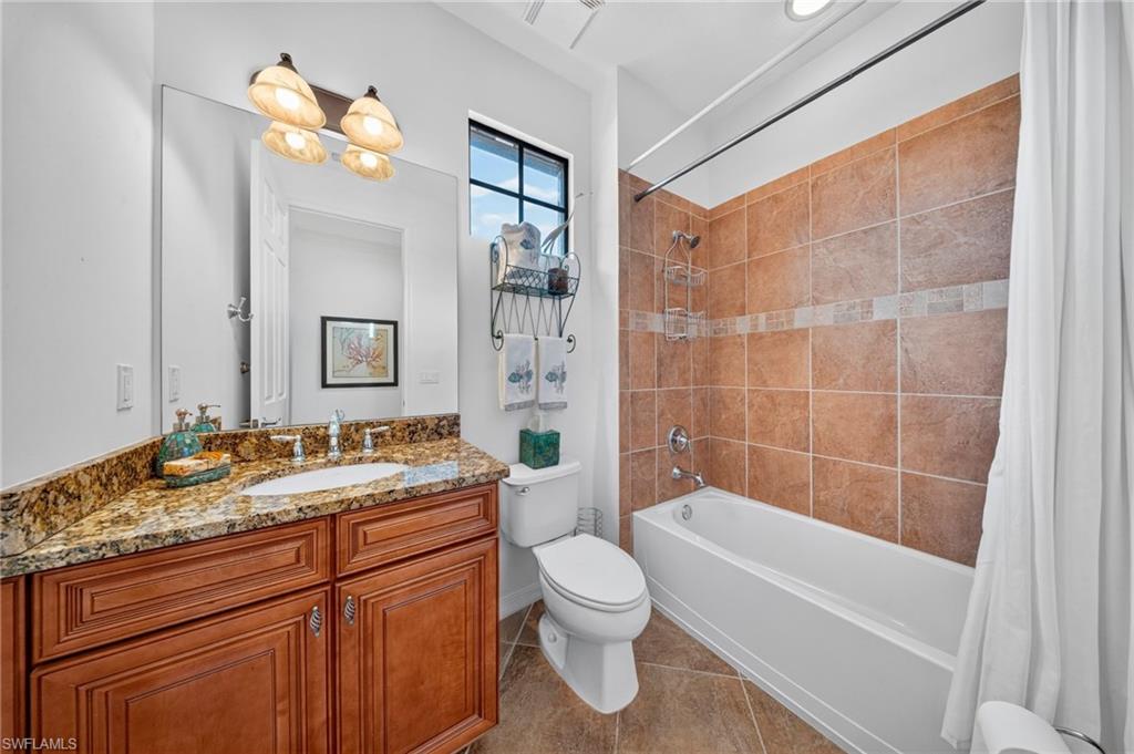 Bathroom featuring a wood-finish vanity with a granite countertop and undermount sink
