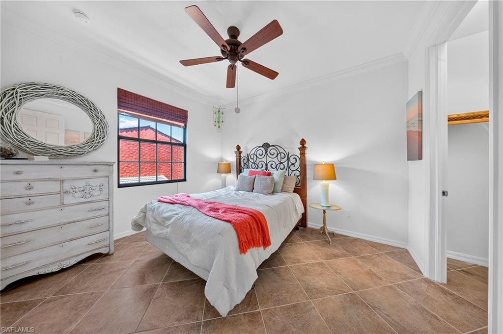 Spacious room featuring tile flooring, a window with red privacy blinds, a ceiling fan, and a built-in closet with a wooden shelf