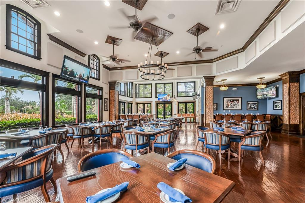 Spacious interior featuring wood-finish flooring, high ceilings, multiple ceiling fans, and a large chandelier