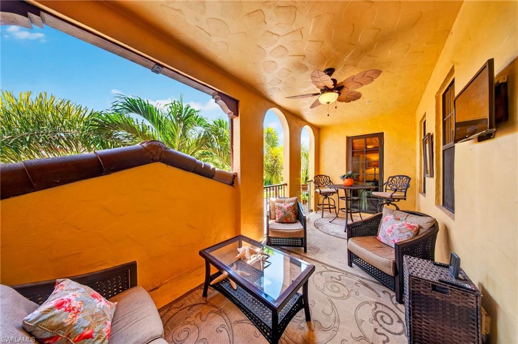 Expansive outdoor balcony featuring arched openings, a decorative ceiling fan, and textured wall finishes