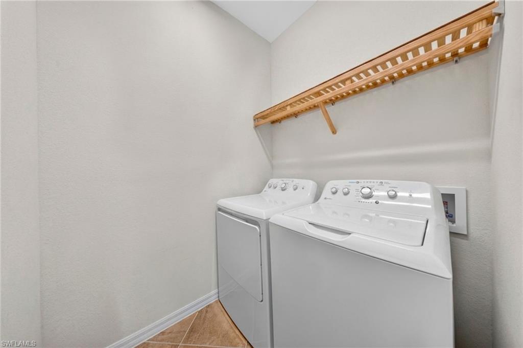 Dedicated laundry area featuring a slatted wood shelf for organization, neutral wall paint, and tiled flooring