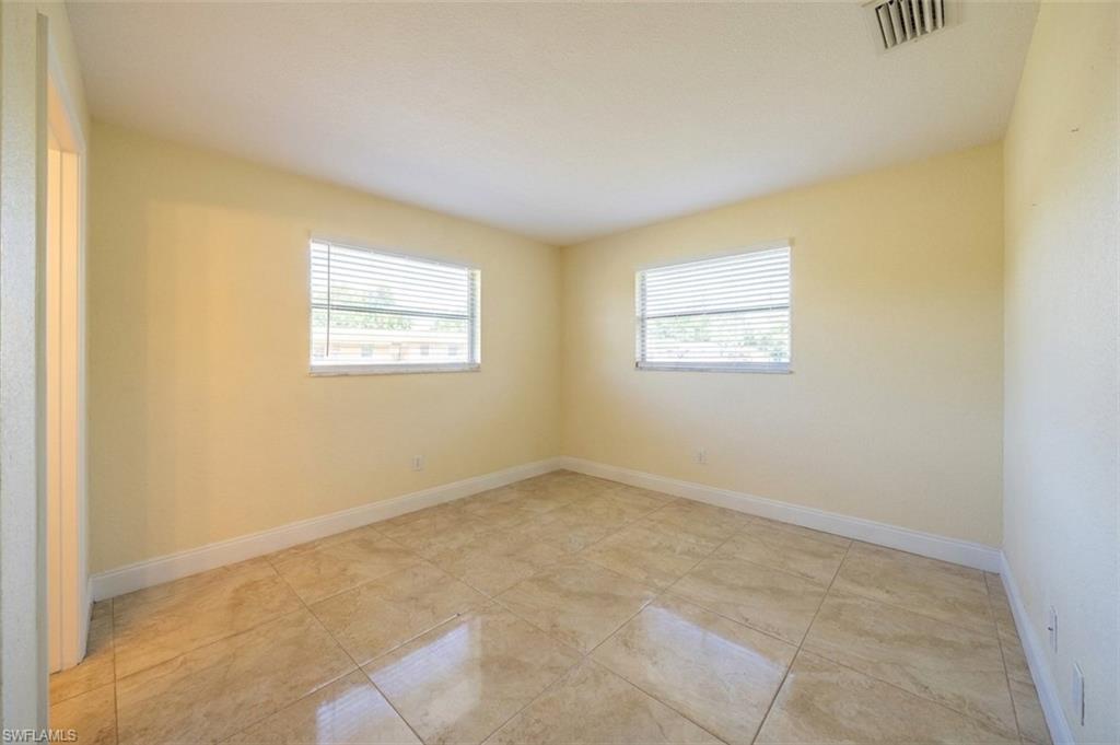 Interior room featuring ceramic tile flooring, two windows with blinds, light-toned wall paint, and white baseboards