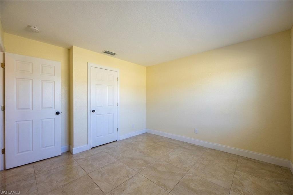 Room featuring light beige tiled flooring, pale yellow walls, white baseboards, and two paneled interior doors