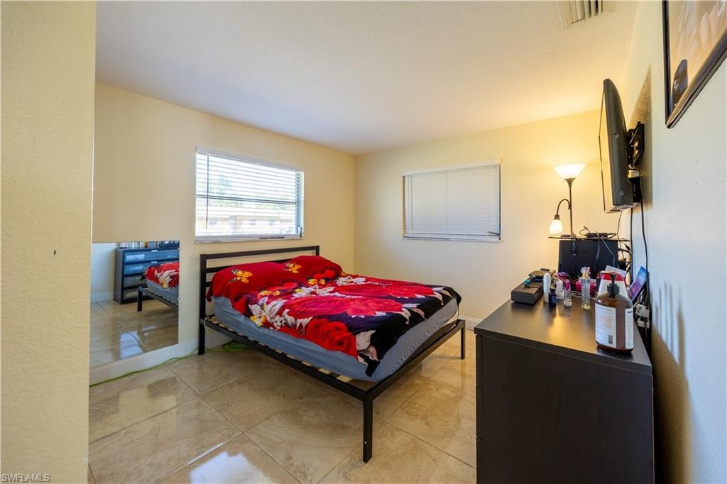 Spacious room featuring tile flooring, two windows with horizontal blinds, and a neutral wall color  AI Generated