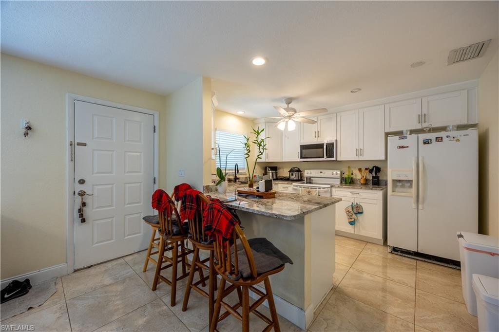 Kitchen featuring an island with a light-colored countertop, white cabinetry, and tile flooring