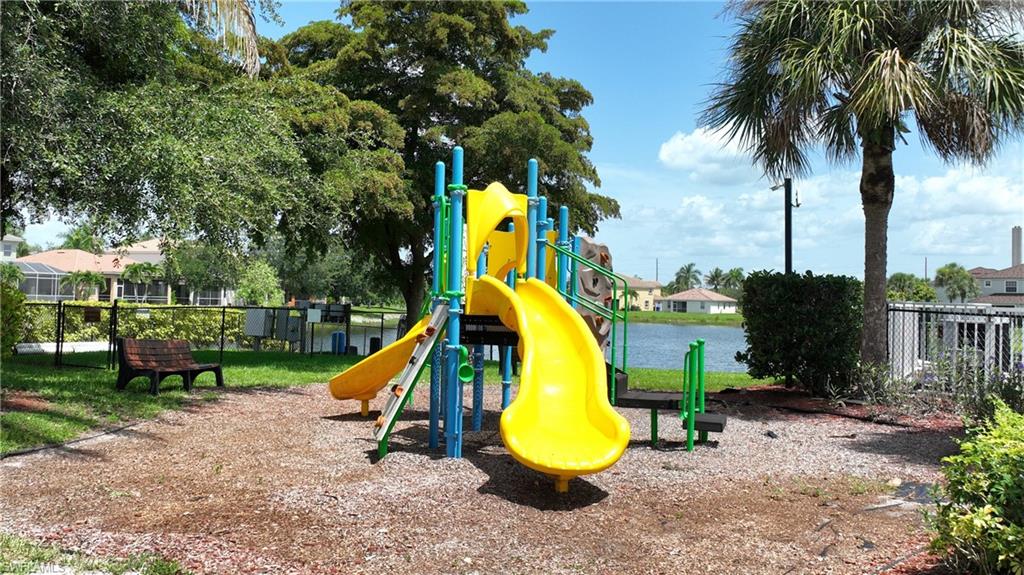 Community playground featuring a multi-level play structure with slides and climbing elements, surrounded by woodchip ground cover