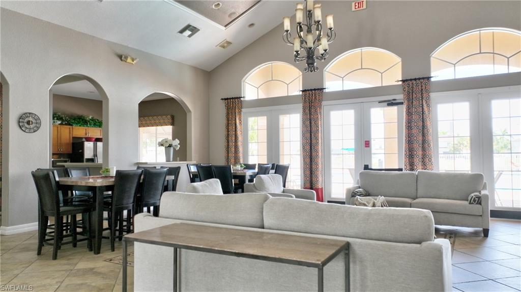 Spacious common area featuring vaulted ceilings, arched doorways, tile flooring, a chandelier, and multiple sets of French doors
