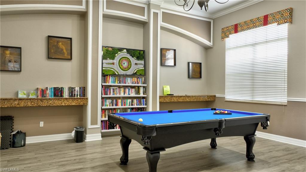Recreation space featuring a billiard table with a blue felt surface, built-in shelving, decorative wall sconces, a large window with blinds, and wood-finish flooring