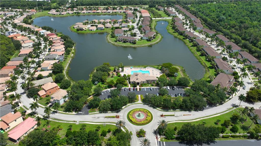 Expansive aerial rendering of a residential community featuring a central roundabout, a large water body with a fountain, a community clubhouse with an outdoor pool, and extensive green spaces