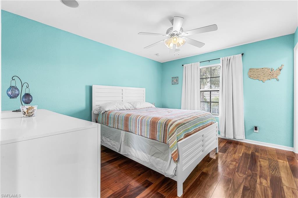 This guest bedroom features a large walk-in closet, wood floors, lighted ceiling fan.