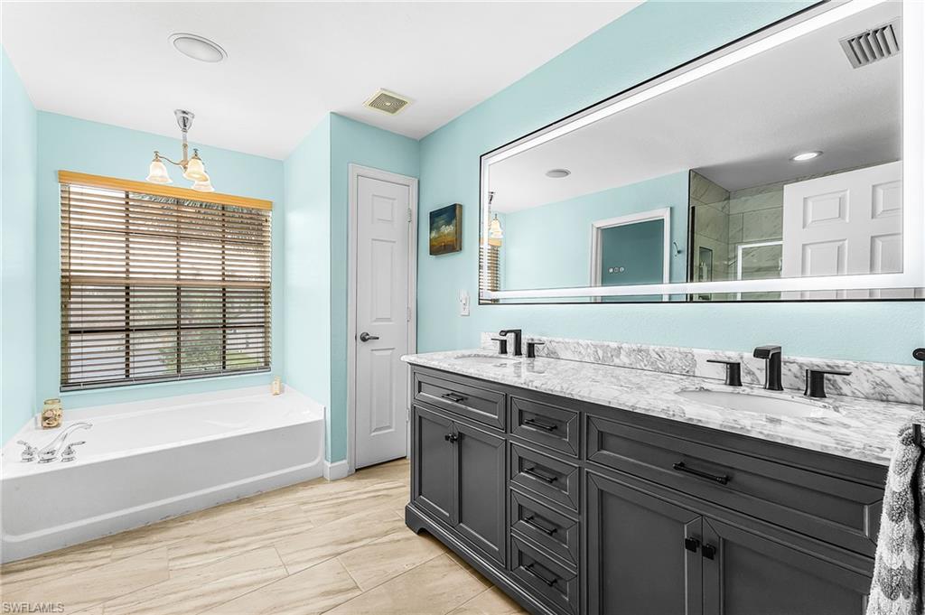 The primary bath features dual sinks, lighted mirror, soaking tub, tile floors, linen closet.
