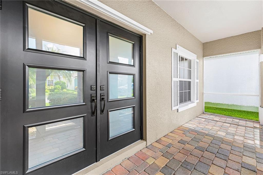 Welcoming entry with new double doors, brick pavers, and screened enclosure.