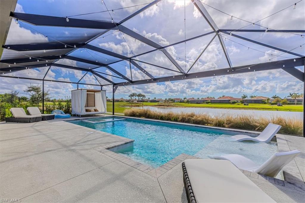 View of swimming pool featuring glass enclosure, a water view, a patio, a pool with connected hot tub, and a sunroom