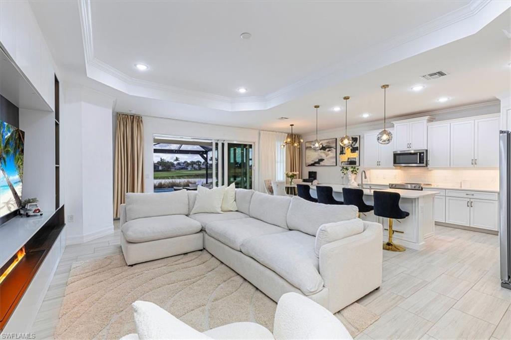Living room featuring crown molding, a chandelier, a raised ceiling, recessed lighting, and wood tiled floors