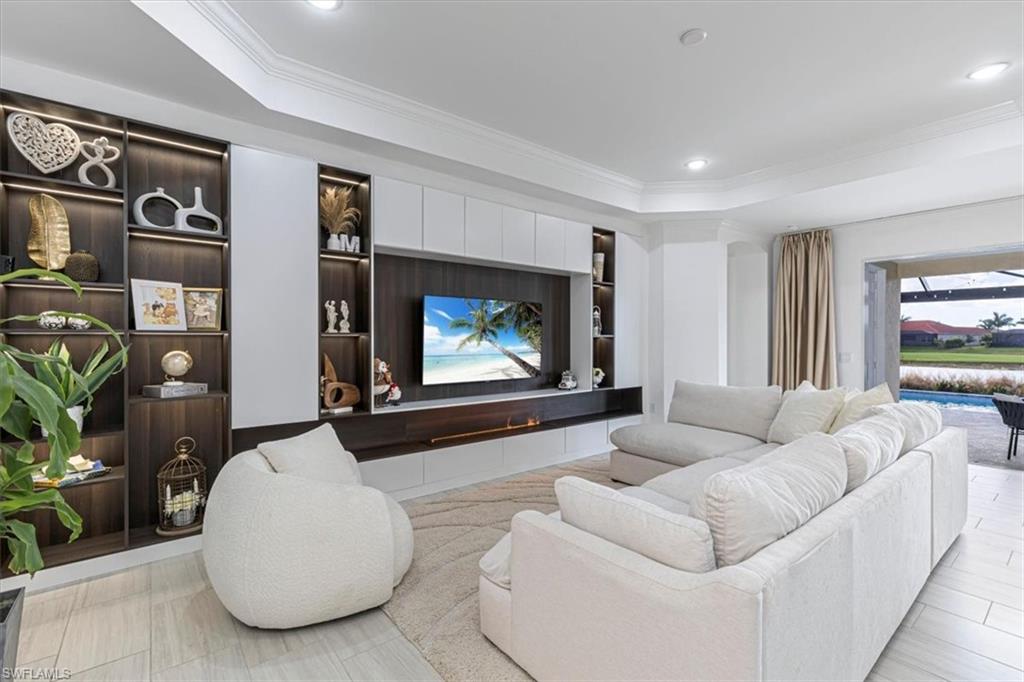 Living room featuring built in features, ornamental molding, a tray ceiling, and recessed lighting