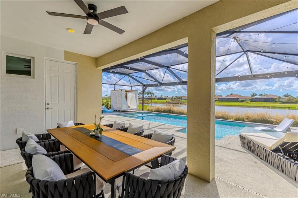 View of patio with an outdoor pool, a water view, glass enclosure, outdoor dining area, and a sunroom
