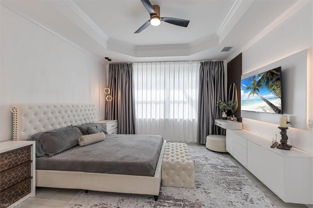 Bedroom with a raised ceiling, ceiling fan, and crown molding
