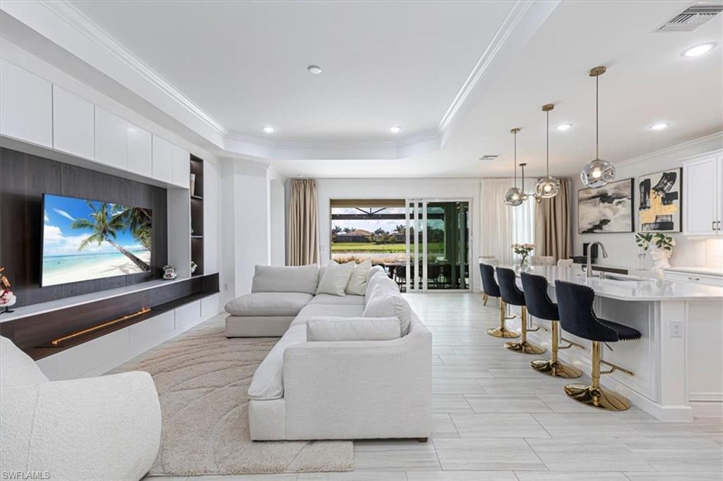 Living room with ornamental molding, a raised ceiling, and built in features