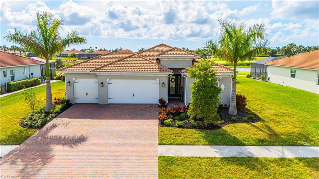 Mediterranean / spanish house with a front yard, an attached garage, stucco siding, decorative driveway, and a tile roof