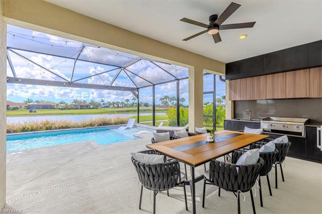 Swimming pool with a sunroom, a patio area, area for grilling, a water view, and outdoor dining area