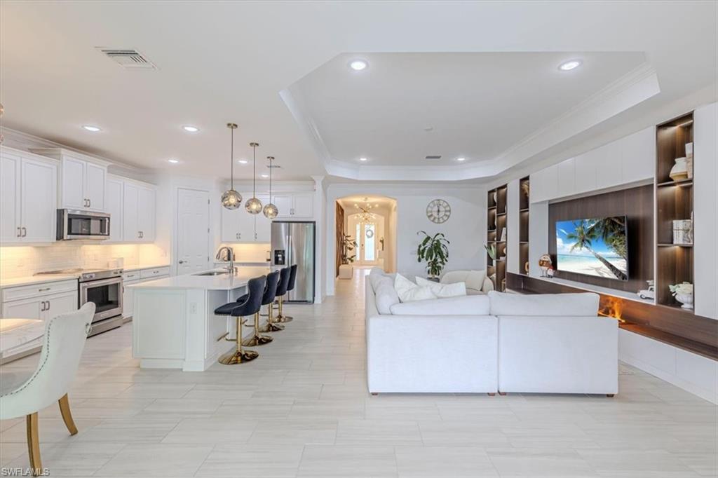 Living area with arched walkways, crown molding, recessed lighting, and a tray ceiling