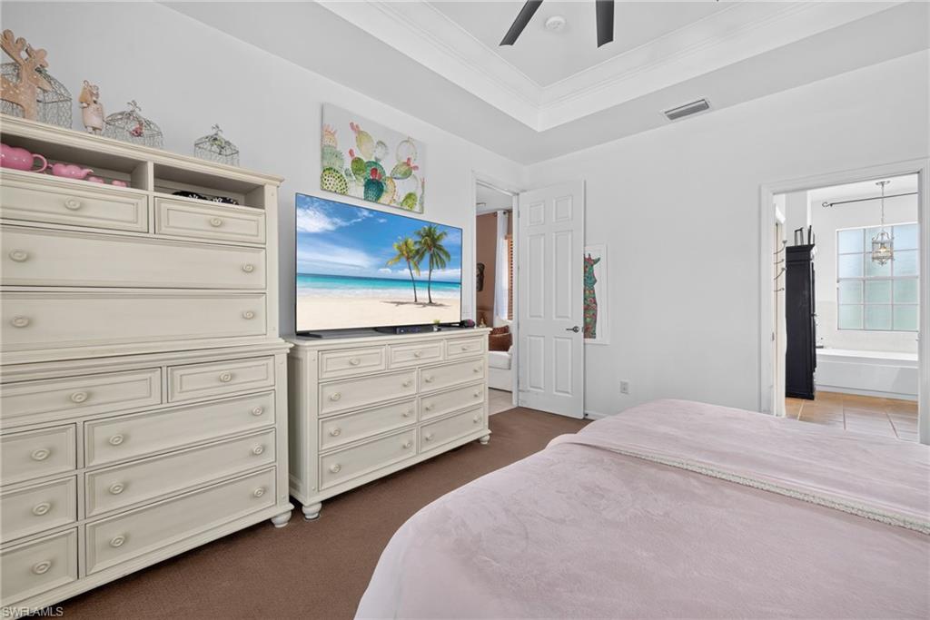 Spacious room featuring a tray ceiling, ceiling fan, and carpeted flooring