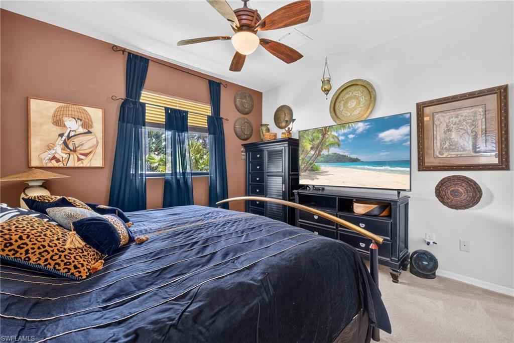 Bedroom featuring a ceiling fan with integrated lighting, a window with horizontal blinds and sheer curtains, and a two-tone wall treatment