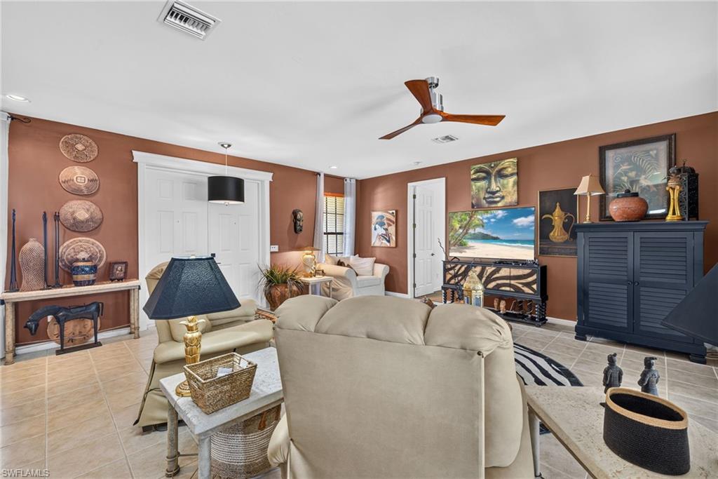 Spacious living area featuring neutral tile flooring, a contemporary ceiling fan, and painted accent walls