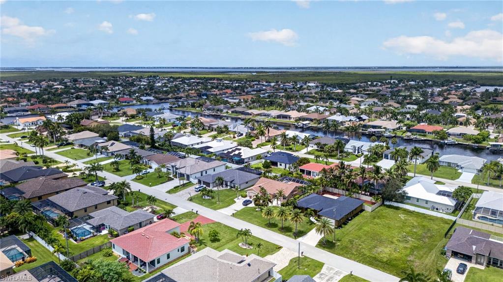 Expansive residential community featuring diverse single-story homes, mature landscaping with palm trees, and canal access