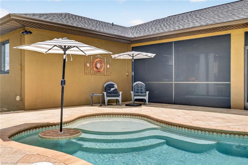 Outdoor living space featuring a swimming pool with integrated steps, a surrounding paved patio, and a screened enclosure