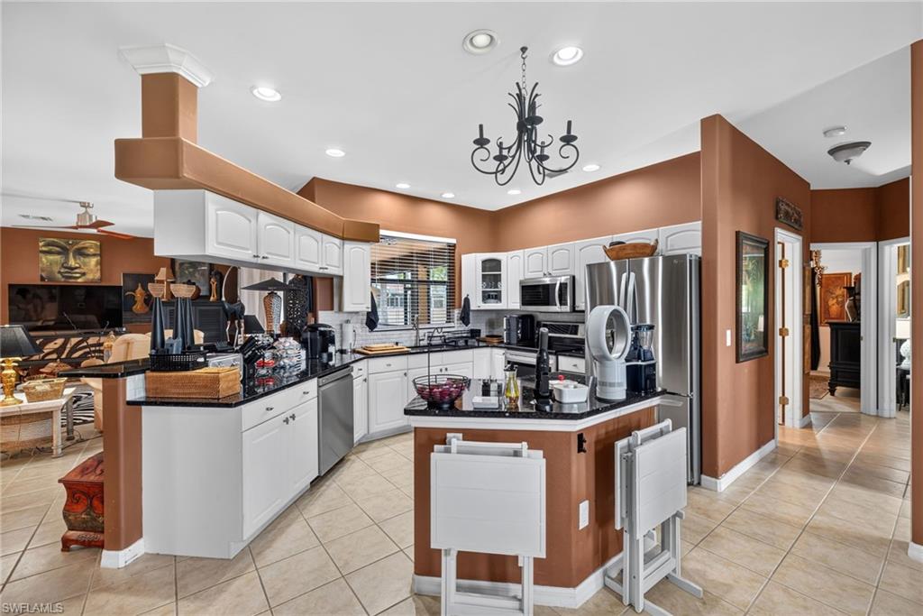 Spacious kitchen featuring white cabinetry, black countertops, stainless steel appliances, and tile flooring