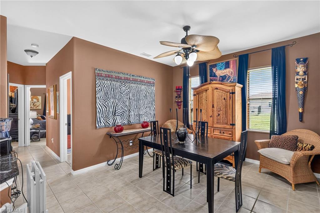 Spacious dining area featuring tile flooring, neutral wall tones, and a ceiling fan with integrated lighting