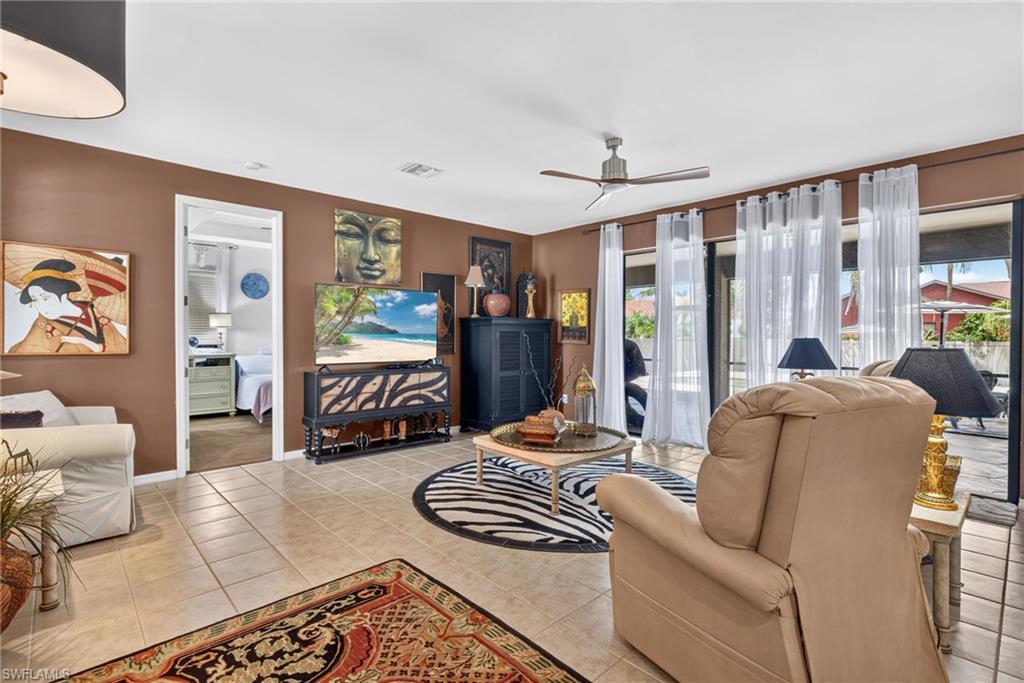 Living space featuring tile flooring, a ceiling fan with light, and sliding glass doors with vertical blinds