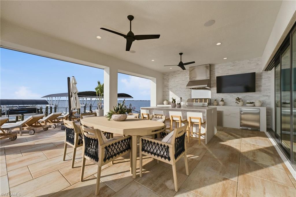 The expansive covered lanai is designed for effortless outdoor entertaining, featuring a striking leathered-granite waterfall island with refrigerator, dual sinks, and a dedicated ice maker. An XO stainless-steel grill with rotisserie and exterior-vented exhaust hood completes this exceptional outdoor kitchen, creating a sophisticated setting for memorable waterfront gatherings.