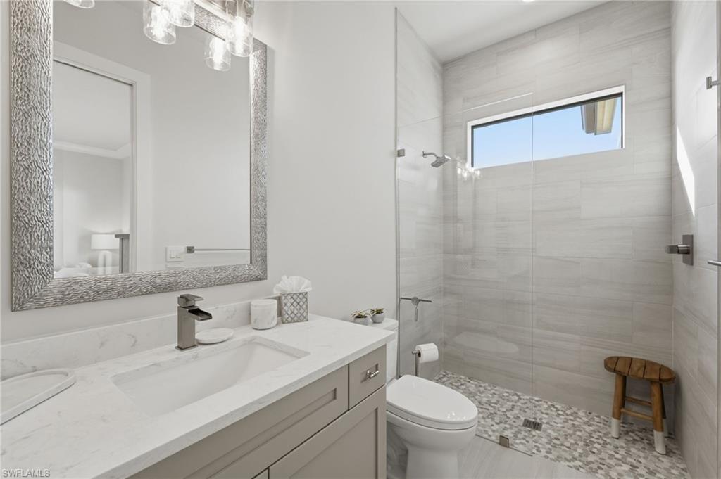 The third ensuite bath is elegantly appointed with a quartz-topped vanity and spacious walk-in shower enclosed by seamless glass. A thoughtfully placed transom window invites soft natural light, creating a bright and serene spa-like retreat.