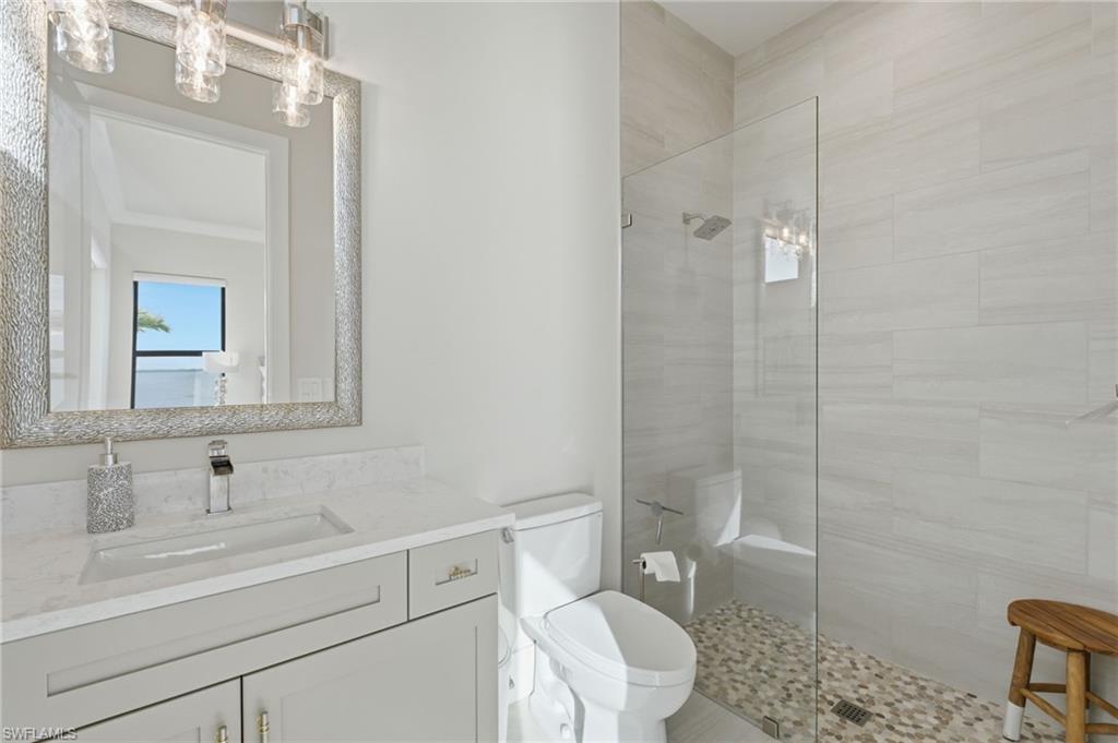 The second ensuite bath features a refined quartz-topped vanity and a spacious walk-in shower enclosed by seamless glass, creating a clean, contemporary retreat with an understated sense of luxury.