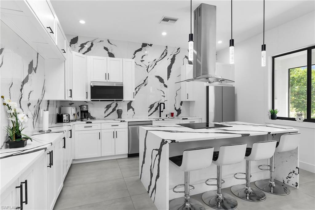 Modern kitchen featuring white shaker cabinetry, stainless steel appliances, and a central island with integrated seating