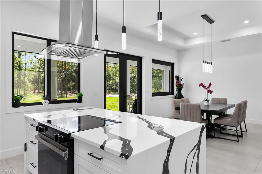 Kitchen island featuring a built-in cooktop, integrated oven, and a contemporary range hood