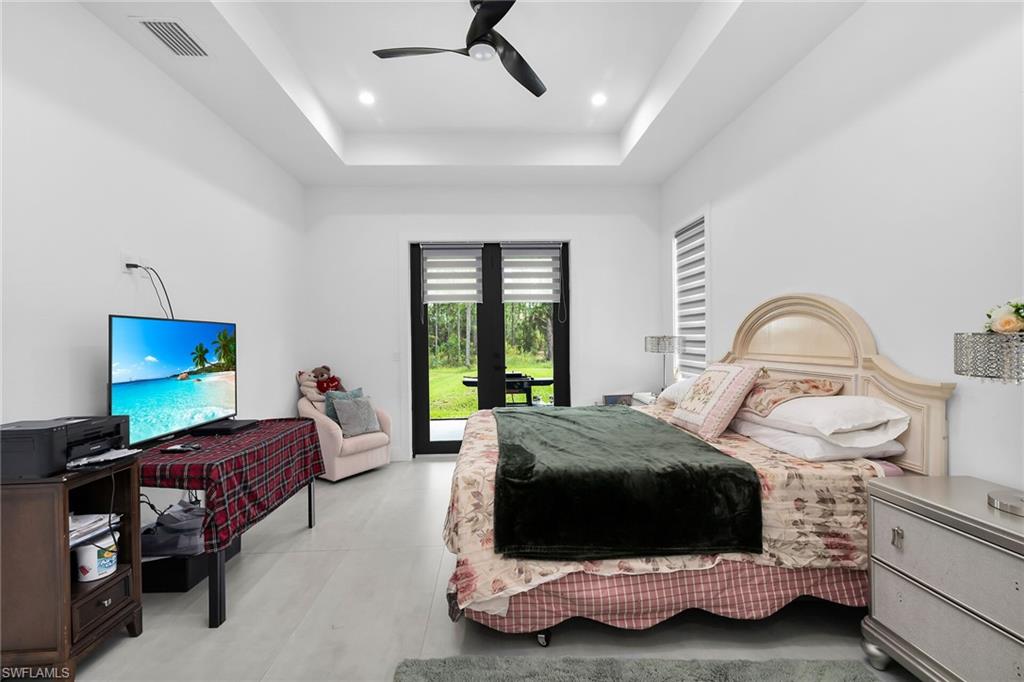 Spacious room with tray ceiling and recessed lighting, featuring light-toned flooring