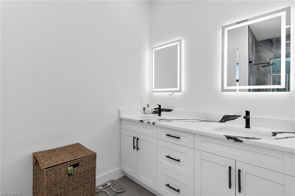Dual vanity with white cabinetry, black hardware, and integrated sinks
